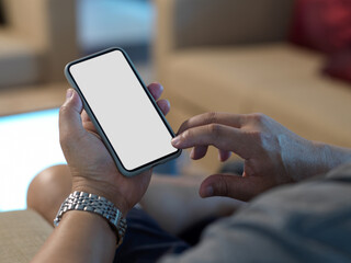 Male hands using mock up smartphone while relaxed sitting on couch