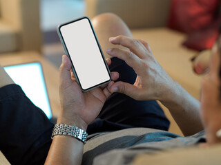 Male hands using mock up smartphone while relaxed sitting on couch