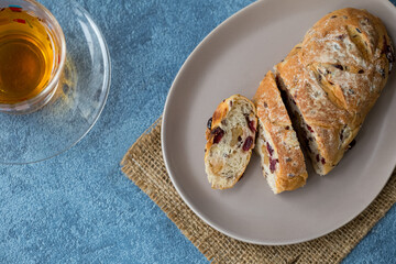 cranberry and walnut bread with tea on blue background