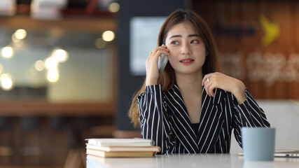 Female office worker talking on the phone while sitting at workplace