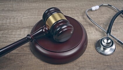 Judge's gavel beside medical stethoscope on wooden table.  Medical law concept.