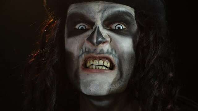 Frightening man in skeleton Halloween makeup screaming, shouting, making faces, trying to scare
