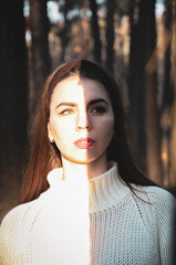 Girl in autumn in the park, a sunbeam falls on her face
