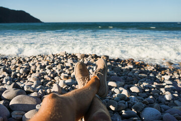 Fototapeta na wymiar Piernas de hombre descansando en la orilla de una playa en verano