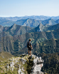 Fototapeta premium Chico observando un paisaje montañoso desde lo alto de una montaña en Asturias 