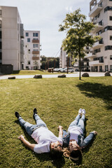 Stylish couple smiling and look at each other lying on green grass