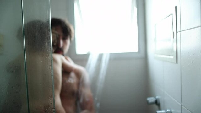 Father entering shower with baby toddler son. Parent and child showering together