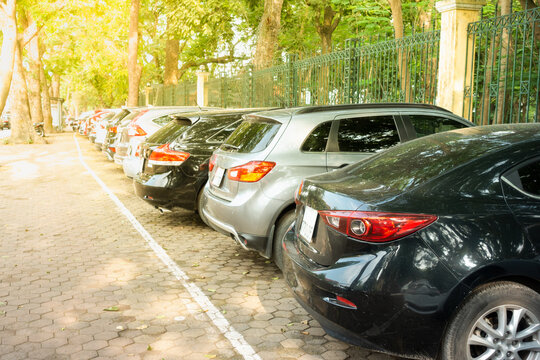 Parallel cars parking on street with green trees