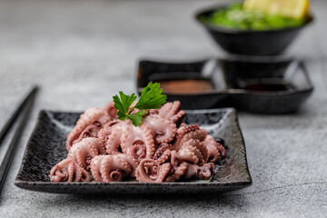 Traditional japanese or seafood concept. Delicious and healthy boiled mini octopus and wakame or seaweed salad with soy sauce and lemon served with chopstick.