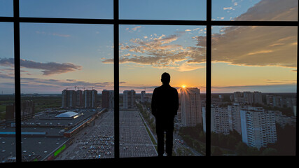 Fototapeta premium The man standing on the building against the city sunset