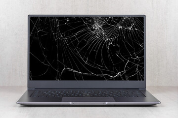 laptop with a broken screen in cracks on a gray background close up front view - 381599840