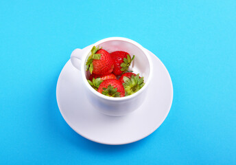 strawberries in a white cup on a blue background. concept of fresh and healthy food, harvesting.