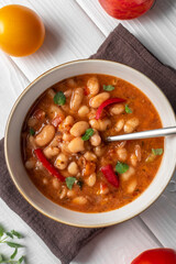 Bulgarian Bean Soup - Bob Chorba, tomatoes, bread and mint on white wooden table. Vertical orientation. Flat lay. Close up.