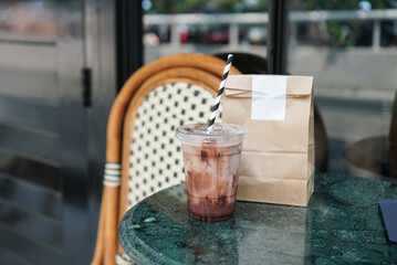 Chocolate latte. A plastic cup of dark chocolate and milk with paper bag. Lifestyle.