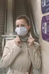 Girl with a medical mask on her face and raised hands in the background of empty escalators and a direction arrow vertical orientation