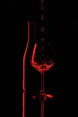 Wine falling into a glass with a bottle in the background
