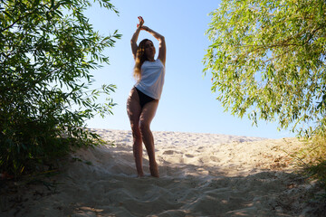 Bottom view of a girl in shorts and a white T-shirt on the sand