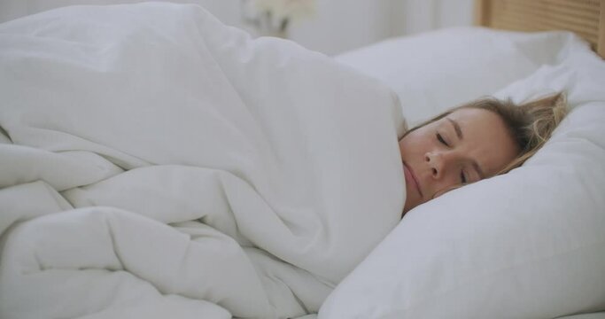 Young woman Lying in bed in the bedroom with plaid shiver freeze feeling cold at home with no central heating problem in chill season, sick ill girl wrapped in blanket having fever flu symptoms