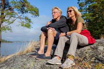 Senior hiking couple looking out on the see thinking of the future in the Swedish archipelago