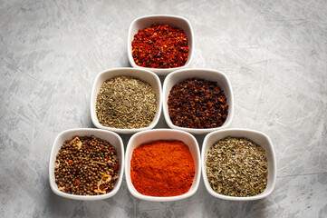 Spices in bowls on a gray concrete background.