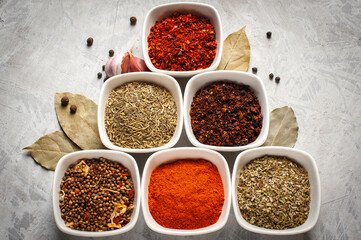 Spices in bowls on a gray concrete background.