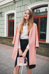 attractive stylish smiling woman walking city street in pink coat spring fashion trend, elegant...