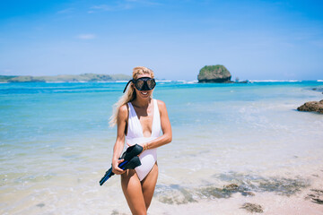 Smiling woman in swimsuit and goggles looking at camera