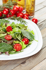 Fresh mixed salad with cherry tomatoes on white plate.