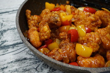 A dishes named Chicken sweet sour on a hot pan over vintage background. usually, people eat with rice.