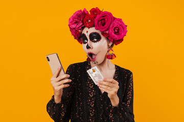 Photo of girl in halloween makeup posing with cellphone and credit card