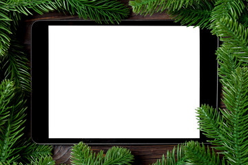 Top view of tablet decorated with a frame made of fir tree on wooden background. New Year time concept