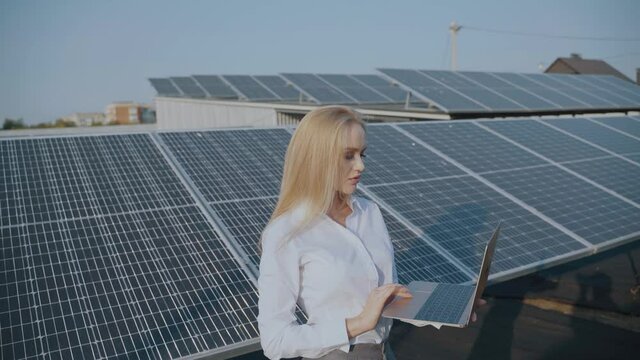 Solar panels and investor with laptop. Business woman with laptop near bule solar cells. Ecological energy for home and business
