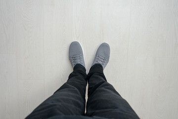 Man is about to take a step, wooden floor, feet in sneakers, close up, top view, copy space