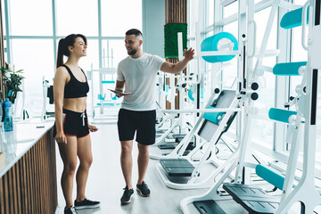 Trainer briefing sportswoman about exercise machines