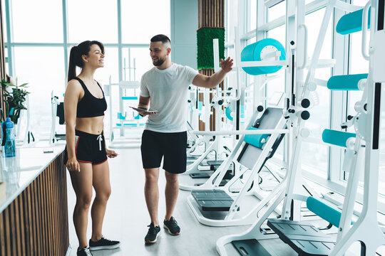 Trainer briefing sportswoman about exercise machines