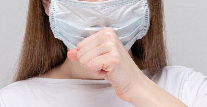 Nurse coughing, girl in medical mask, women's hand, cropped image, closeup, 16:9