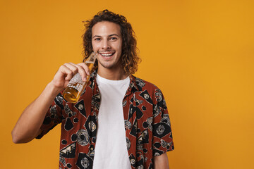 Image of cheerful young man smiling and drinking bear