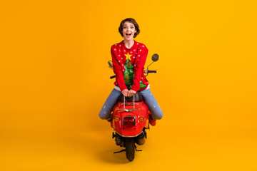 Obraz premium Full length photo of excited girl sit scooter backside on x-mas travel theme party masquerade wear red christmas tree pullover jumper denim jeans isolated bright shine color background