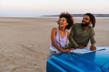 Obraz premium Image of joyful african american couple examining map while travelling on desert
