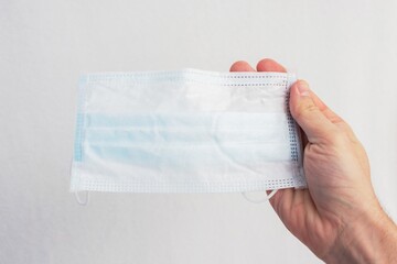 Person hand shows a blue medical mask, hand close up, cropped image, copy space