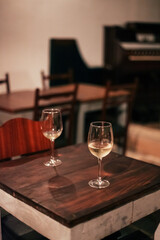 Two glasses of white wine on a wooden table in a cozy dark bar