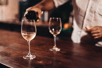 Two glasses of white wine on a wooden table in a cozy dark bar