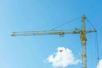 Construction crane on blue sky background with clouds