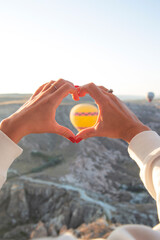 Women's hands in the shape of a heart against the background of flying balloons in the sky of Cappadocia. Holidays in Turkey, travel during a pandemic