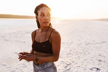 Image of sportswoman using earphones and cellphone while working out