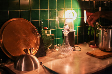 A process of making a cocktail in a bar - orange, lime, cocktail tools on a wooden table with bar light