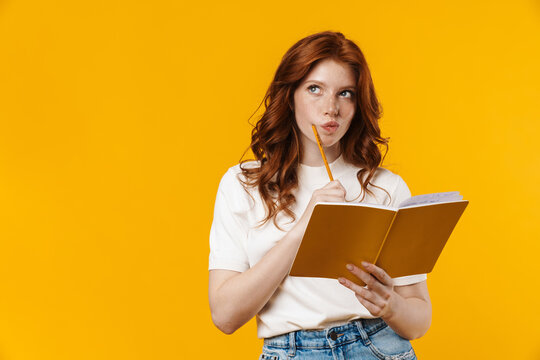 Image of ginger serious girl thinking and holding exercise book