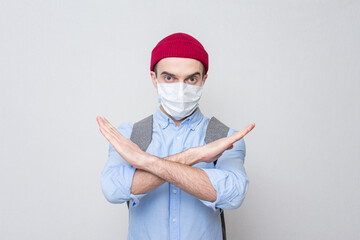 Teen student shows a taboo sign with his hands, white background, portrait