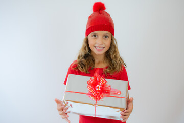 Picture of happy little girl child standing isolated over white background. Looking camera holding gift box surprise.