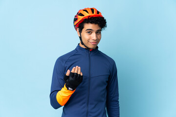 Venezuelan cyclist man isolated on blue background inviting to come with hand. Happy that you came
